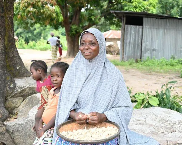 A woman seated outdoors with a tray of groundnuts