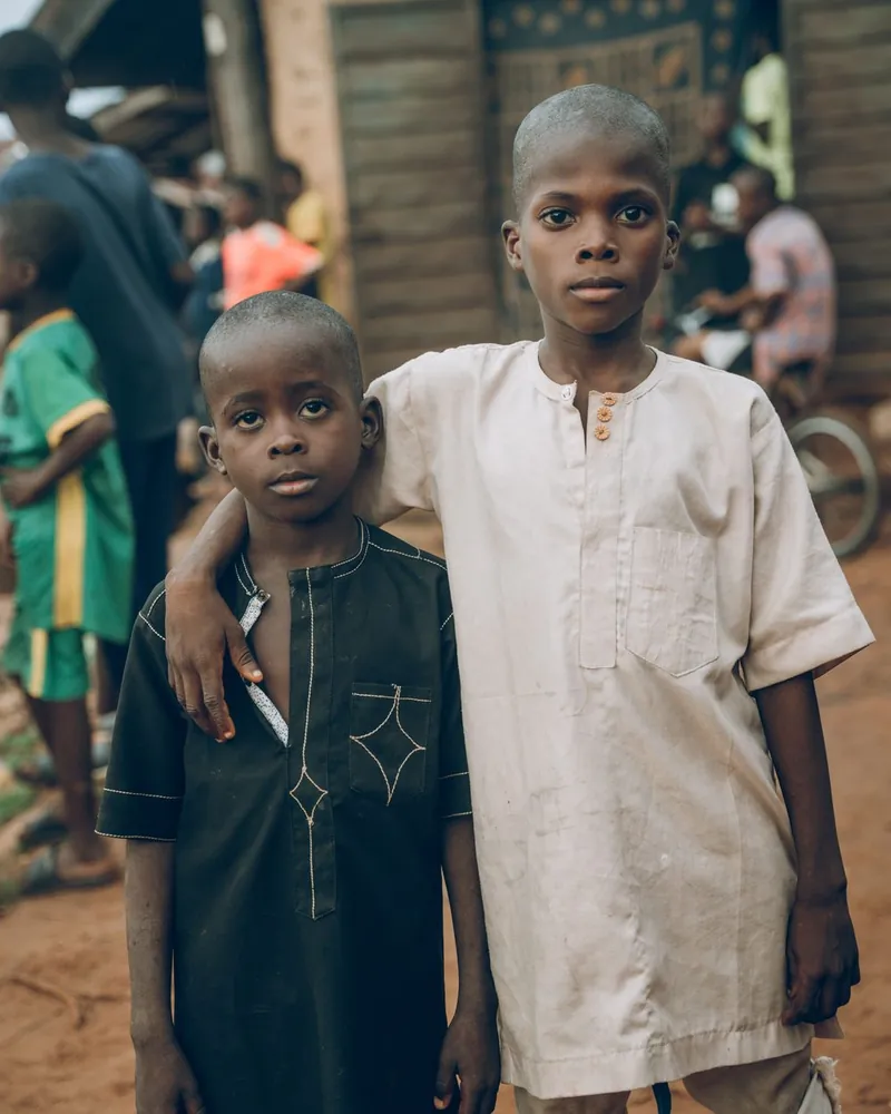Two boys in kaftans standing on a busy community street